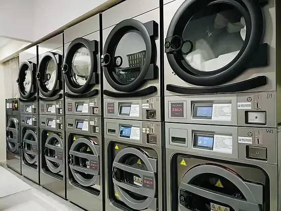 A close-up of stacked commercial washer and dryer glass doors in a laundromat